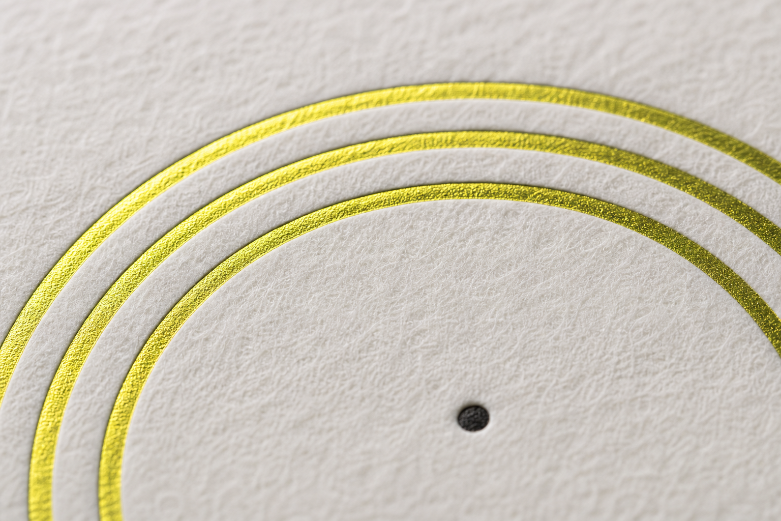 Three chartreuse foil arcs stamped into textured paper